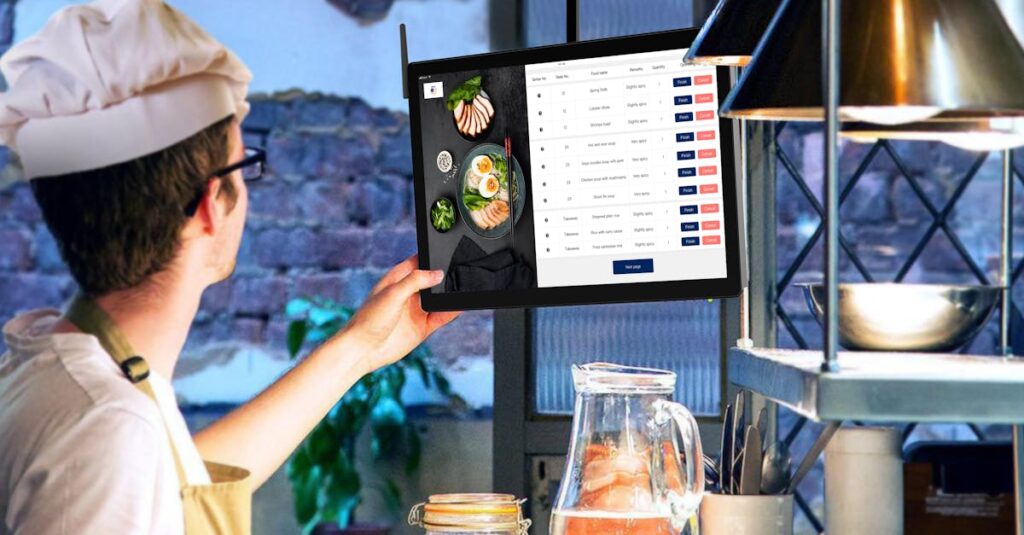 Chef using a tablet to manage kitchen orders in a restaurant setting.