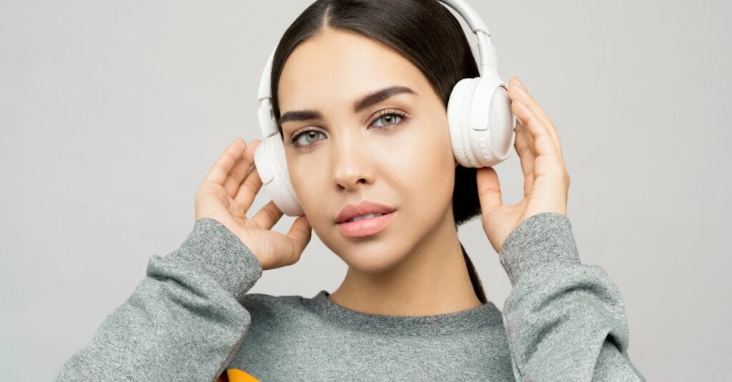 Portrait of a young woman wearing headphones, enjoying music indoors with a casual expression.