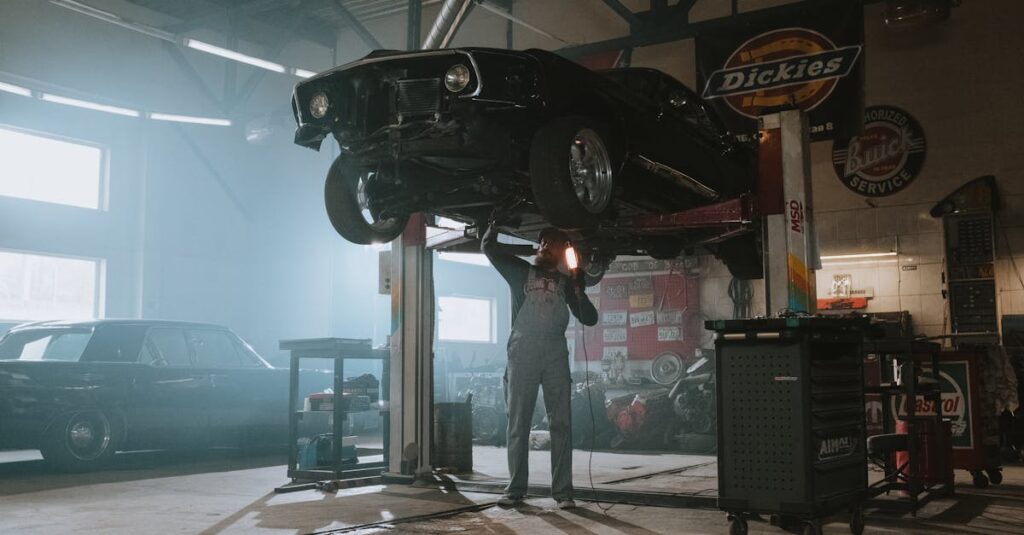 Male mechanic using a light to inspect a classic car lifted in an automotive garage.