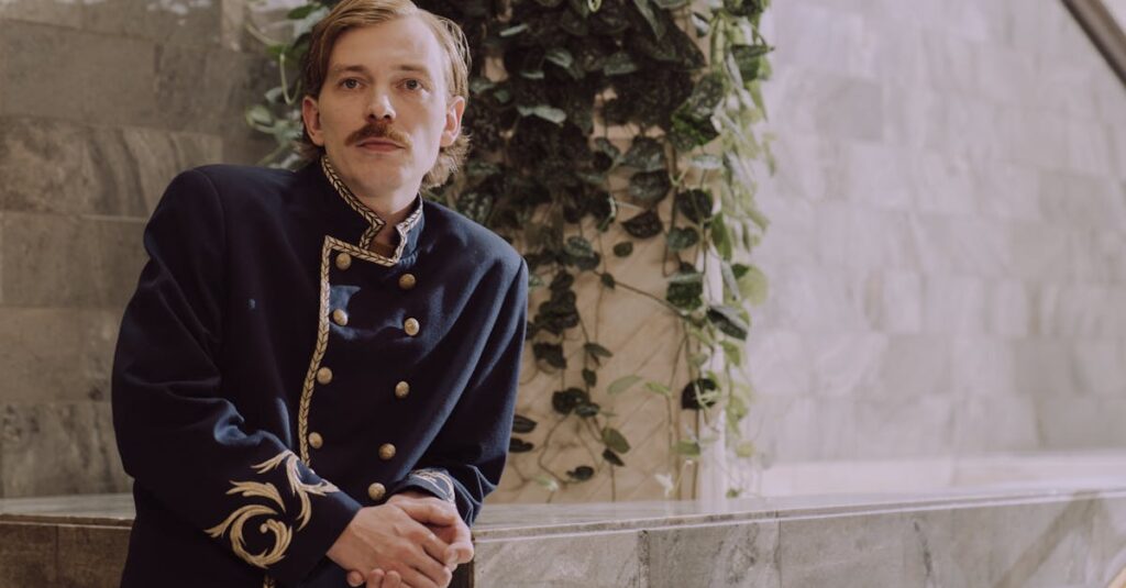 Elegant portrait of a hotel porter in uniform with a classic setting and leafy backdrop.