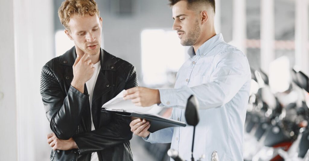 Two adults discussing purchasing options at a motorcycle dealership.