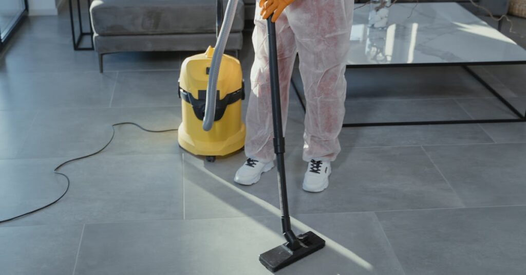 A professional cleaner in protective gear vacuuming the floor in a modern living room.