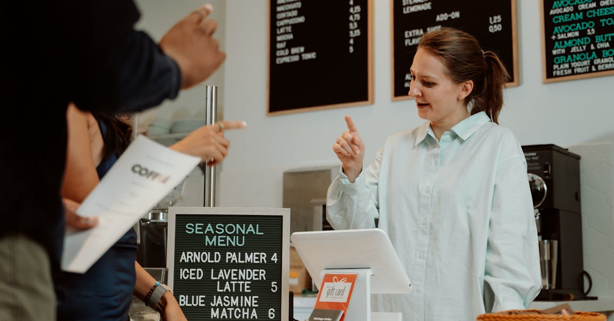 Barista serving customers at cafe counter with seasonal menu board.