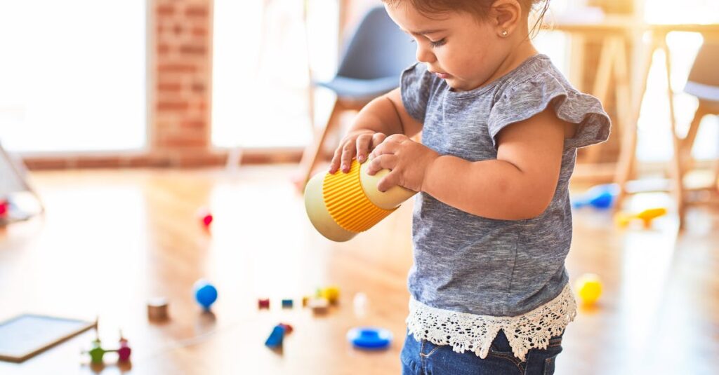 Cute toddler playing with toys in a bright nursery setting, enjoying playtime.